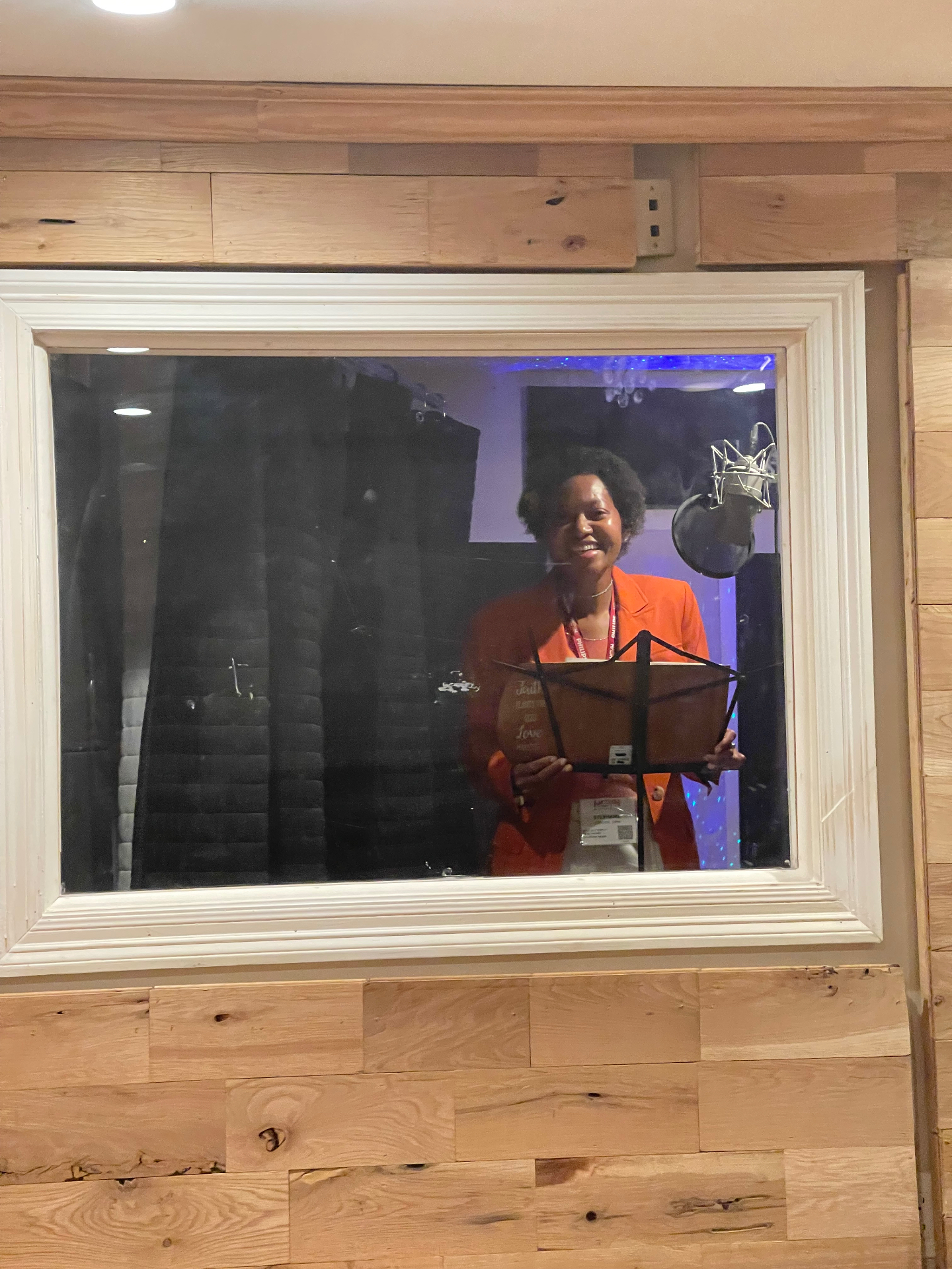 Dr. Stephanie Jupiter smiling inside the recording booth behind the studio glass